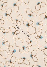 Tessuto bianco con contorni di fiori marroni e blu chiaro; presenta il testo "Manila Grace" tra i motivi floreali. Texture morbida.