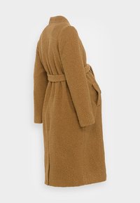 Brązowy teksturowany płaszcz wierzchni z paskiem w talii, długimi rękawami i kieszeniami. Posiada kołnierz i sięga do kolan.