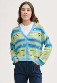 Háčkovaná cardigan v zelenomodrých pruhoch s výstrihom do V, gombíkmi a voľným strihom. Obsahuje textúrovaný, otvorený pletený dizajn.
