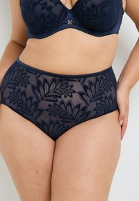 Culotte taille haute bleu marine avec motif en dentelle florale et une ceinture élastique lisse. Design texturé avec des détails transparents tout au long.
