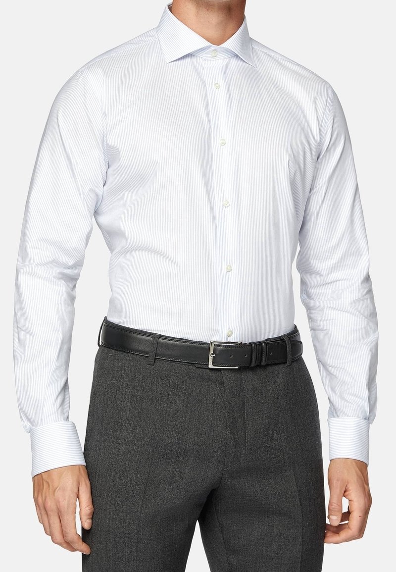 Vit skjorta med ljusblå ränder, knappad krage, långa ärmar, i kombination med mörkgrå byxor och ett svart läderbälte.