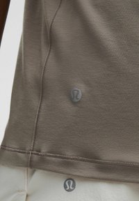 Nahaufnahme eines braunen Sporttops und einer weißen Hose, die die Lululemon-Logos und die detaillierte Naht auf dem Stoff zeigen.