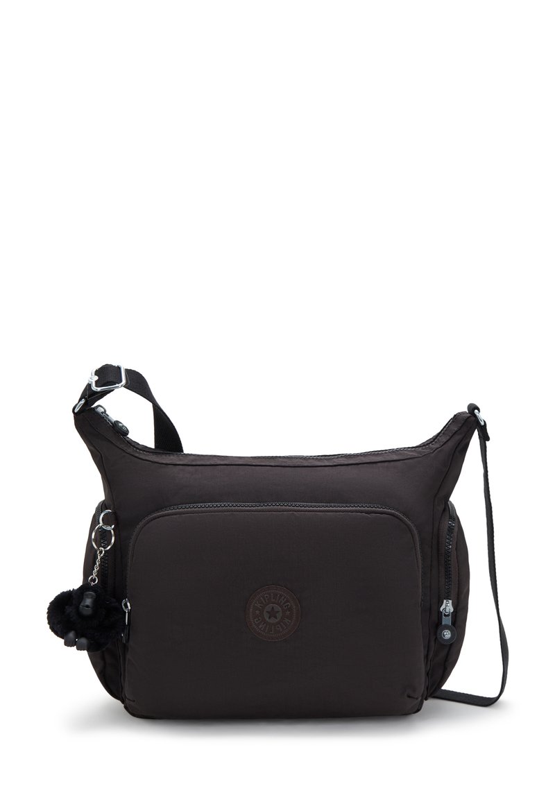 Dark brown fabric shoulder bag with a zippered main compartment, front pocket, and a decorative furry charm attached. Plain design, adjustable strap.