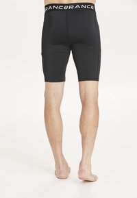 Svarta tajta shorts med en slät textur och elastisk midja som har vit branding. Klippta till midtlårslängd för en åtsittande passform.