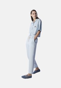 Camicetta azzurro chiaro corta con maniche corte e dettaglio a stella, abbinata a pantaloni azzurro chiaro e ballerine in suede blu con fibbie.