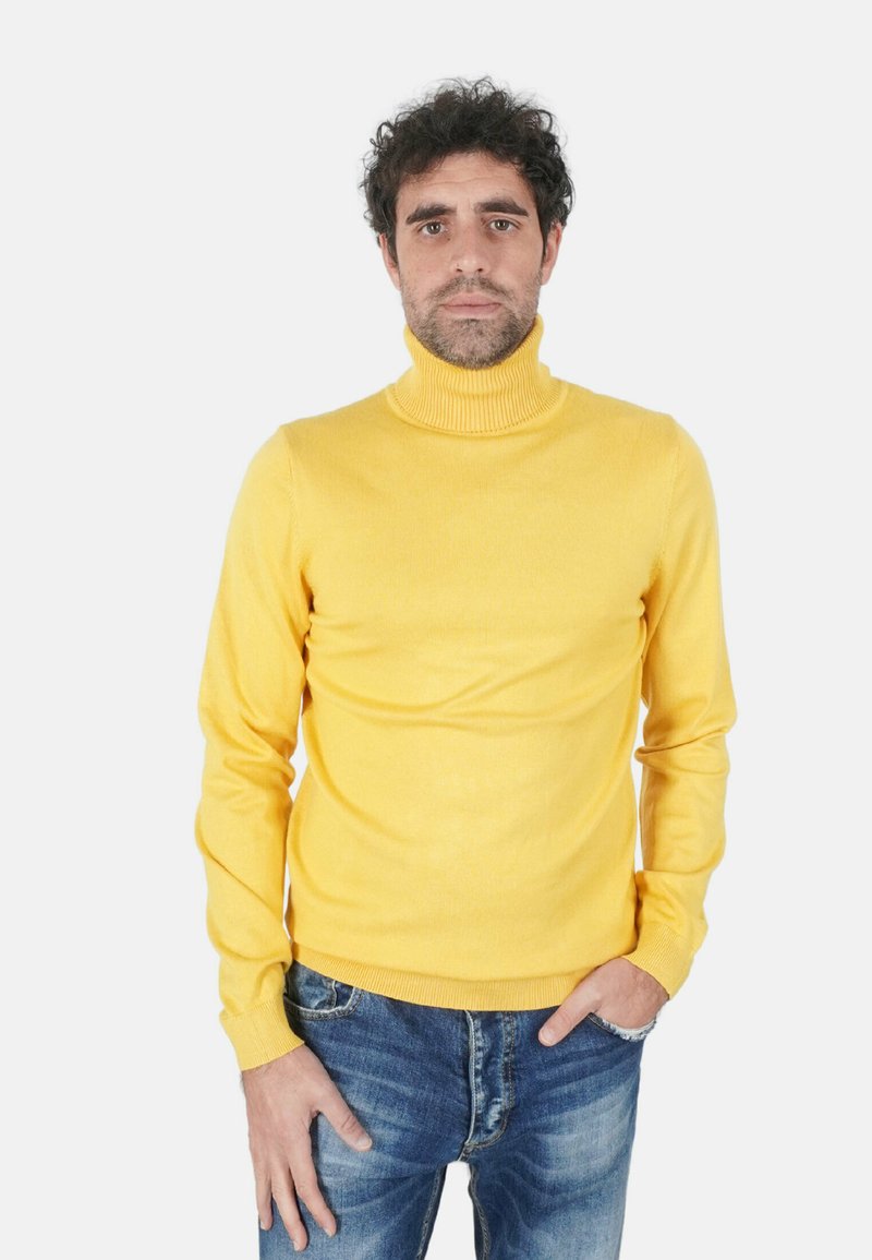 Maglione giallo a collo alto in tessuto morbido, design aderente, con maniche lunghe, abbinato a jeans blu slavati.