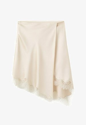 Satenasta krilca kremne barve z obrobo iz čipke ob asimetričnem robu, obešena na belem ozadju.