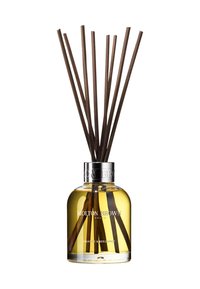 Reed diffuser with clear glass bottle, silver collar, yellow liquid, and eight brown reeds. Label reads "Molton Brown, Orange & Bergamot."