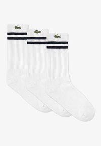 Chaussettes blanches côtelées à hauteur de cheville avec deux rayures bleu marine en haut et un logo de crocodile vert sur le côté. Trois paires incluses.