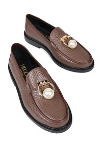 Brązowe skórzane mokasyny o teksturowym wykończeniu, ze złotymi elementami i dużą perłą na pasku, z czarną podeszwą.