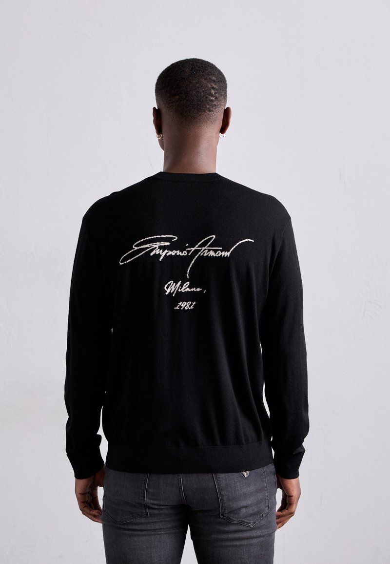 Jersey negro de manga larga con firma bordada en blanco y el año "1981" en la parte posterior, hecho de una tela suave con puños acanalados.