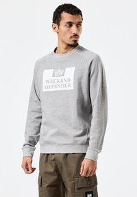 Halli pusa ümar kaelusega. Suur valge kirjaga "WEEKEND OFFENDER" ja krooni logo. Pehme tekstuur, lõdvestunud lõige ja soonilised varrukaservad.