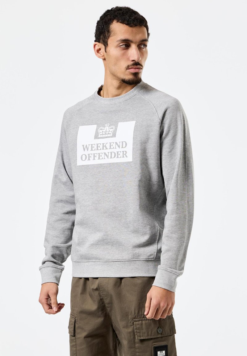 Halli pusa ümar kaelusega. Suur valge kirjaga "WEEKEND OFFENDER" ja krooni logo. Pehme tekstuur, lõdvestunud lõige ja soonilised varrukaservad.