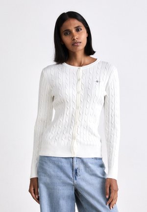 Cardigan en tricot blanc avec un motif en relief, encolure ronde et boutons sur le devant. Coupe décontractée avec des poignets et un ourlet côtelés.