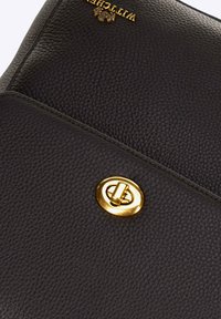 Borsa a mano in pelle nera con superficie testurizzata, caratterizzata da un fermaglio circolare color oro e logo in rilievo sulla parte superiore.