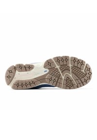 Shoe sole featuring a textured rubber tread with a mix of dark blue and light cream colors, and a sturdy design for grip and durability.