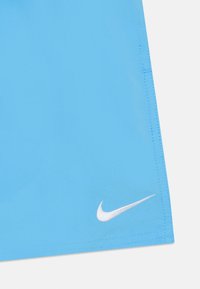 Plave atletske šortse izrađene od glatkog materijala, s bijelim Nike logom na donjem rubu i ravnim šavovima za izdržljivost.