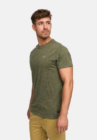 Oliwkowa koszulka typu crew neck z teksturowanym wzorem i małym logo po lewej stronie klatki piersiowej. Casualowy krój z krótkimi rękawami i zaokrąglonym dołem.