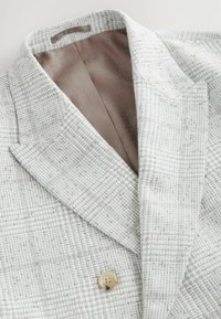 Lys grå tekstureret blazer med reverskrave, der har en enkelt knaplukning og en glat beige inderfor.