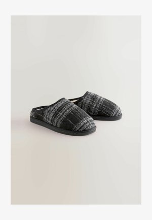 Fekete és szürke kockás papucs, puha gyapjú béléssel, lekerekített orral és fekete gumitalppal; a könnyű felhúzáshoz tervezve.