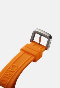 Oranges Gummiband für die Uhr mit einer silbernen Metallschnalle, die den eingravierten Markennamen trägt. Das Band hat eine glatte Textur und zwei horizontale Linien.