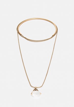 Gouden halsketting met een dunne ketting en een sierlijke zetting die een heldere, ronde edelsteen hanger op een witte achtergrond houdt.