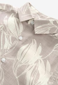 Camicia lavanda leggermente testurizzata con un motivo botanico di foglie bianche, colletto classico e bottoni bianchi lungo il davanti.