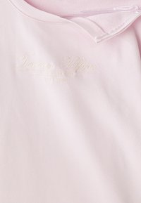 Light pink pullover with a ribbed collar. Features tonal embroidered logo, "Tommy Hilfiger," with New York City and establishment year below.