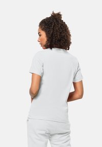 T-shirt en coton blanc avec un col rond et des manches courtes. Le tissu semble doux, avec une texture lisse et sans motifs ni logos visibles.