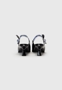 Chaussures slingback en cuir verni noir avec un bout pointu et un talon carré. La bride de cheville présente un ruban imprimé avec le logo "KARL LAGERFELD".