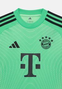 Maillot de gardien de but vert avec des accents noirs, arborant le logo Adidas, l'emblème du FC Bayern München, des motifs texturés et un col ras du cou.