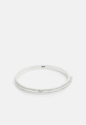 Sølvfarvet armbånd med to rækker klare krystaller og et lille DKNY-logo på en hvid baggrund.