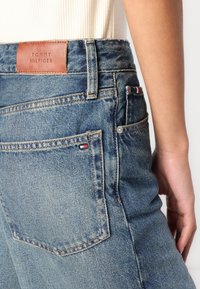 Τζιν παντελόνι σε ανοιχτό γαλάζιο ύφασμα, με δερμάτινο λογότυπο, ελαφριά ξεθωριάσματα και μικρό χρωματιστό λογότυπο στην πίσω τσέπη.