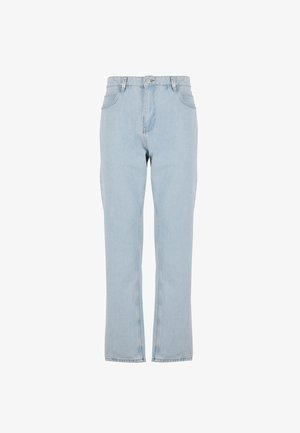 Φωτεινά γαλάζια τζιν με ίσιο κόψιμο που φοριούνται από ένα άτομο που στέκεται, σε συνδυασμό με λευκά αθλητικά παπούτσια και μια λευκή πουκάμισο κρυμμένη μέσα.