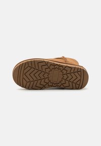 Chaussure en daim marron avec une semelle en caoutchouc texturé présentant un motif en zigzag. Accentuée par des coutures et une finition douce sur le dessus.