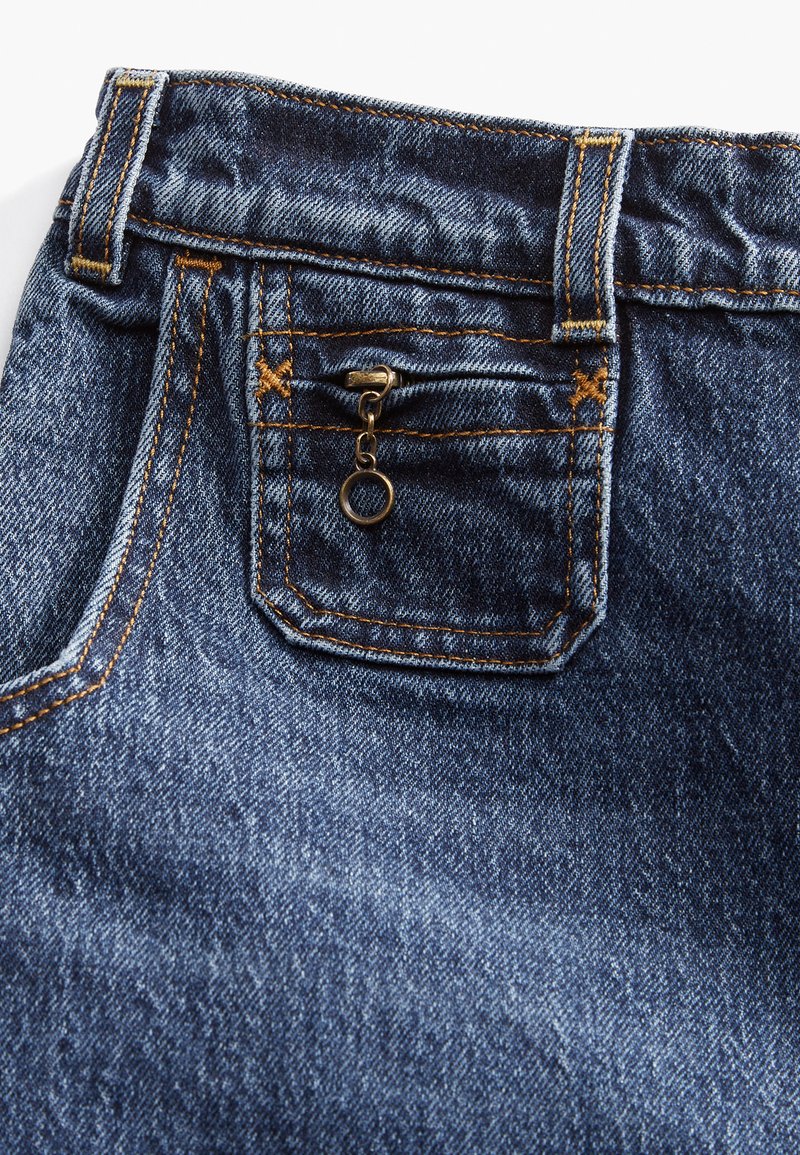 Jean en denim de couleur bleu foncé, avec des surpiqûres orange contrastées. Détails remarquables comprenant une petite poche zippée et une ceinture robuste.