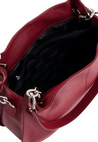 Red leather handbag with a textured finish, silver hardware, a zip pocket, and a branded interior featuring a dark lining.