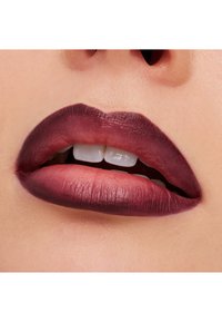 Dype bær-leppestift påførte fyldige lepper, med en matt finish. Overleppen er mørkere, mens underleppen viser en subtil gradient til lysere toner.