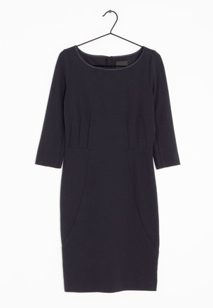 Czarna sukienka do kolan z rękawami do połowy przedramienia, okrągłym dekoltem, przeszyciami, zawieszona na czarnym wieszaku na ubrania na białym tle.