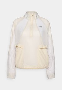 Veste légère à col zippé mi-hauteur en crème, dotée de deux poches frontales et de textures de tissu contrastantes subtiles. Logo New Balance présent.
