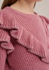 Rosa stickad tröja med en texturerad kropp, rund halsringning och volangdetaljer längs axlarna med metallictråd.