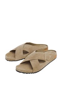 Béžové semišové sandále na slip-on s krížovými popruhmi, mäkkou textúrou a pevným čiernym gumovým podrážkou. Obsahujú detaily s výrezmi a prirodzený povrch.