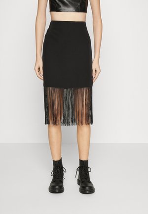 Sort blyantskirt med frynset kant, lavet af struktureret stof. Kombineret med sorte snørebåndsstøvler, som fremviser en tætsiddende silhuet.