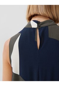 Ärmelloses Top in Marineblau, Grün und Weiß mit hohem Kragen, fein strukturiertem Stoff und Knopfverschluss am Nacken.