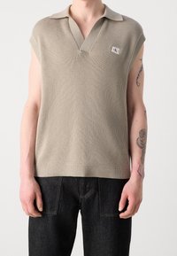 Beige gerippte ärmellose Polohemd mit Kragen und einem kleinen Logo-Patch. Es hat ein strukturiertes Strickdesign und eine lockere Passform.