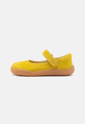 Ballerines en daim jaune avec un bout arrondi et une bride Velcro. Dotées d'une semelle en caoutchouc beige texturé et d'une doublure intérieure lisse.