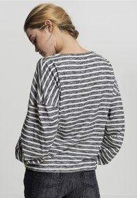 Gestreiftes Langarm-Oberteil in Schwarz und Weiß, mit lockerer Passform, Rundhalsausschnitt und weichem Stoff, mit überschnittenen Schultern und lässigem Design.