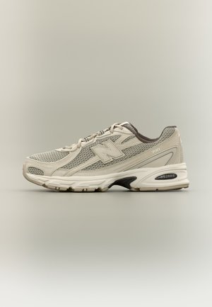 Béžovo-sivá bežecká obuv zo sieťoviny s bielou podrážkou, šnurovacím dizajnom a textúrovaným gripom, obsahujúca logo "N" a detail odpruženia "ABZORB".