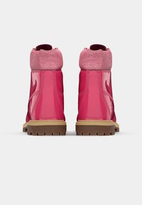 Botas cor-de-rosa com acabamento brilhante, apresentando um colarinho texturizado cor-de-rosa e uma sola robusta castanha. A vista traseira destaca os detalhes em relevo no colarinho.
