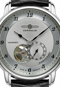 Silver automatic watch with a textured dial, black hour and minute hands, and a sub-dial, featuring a visible movement and black leather strap.